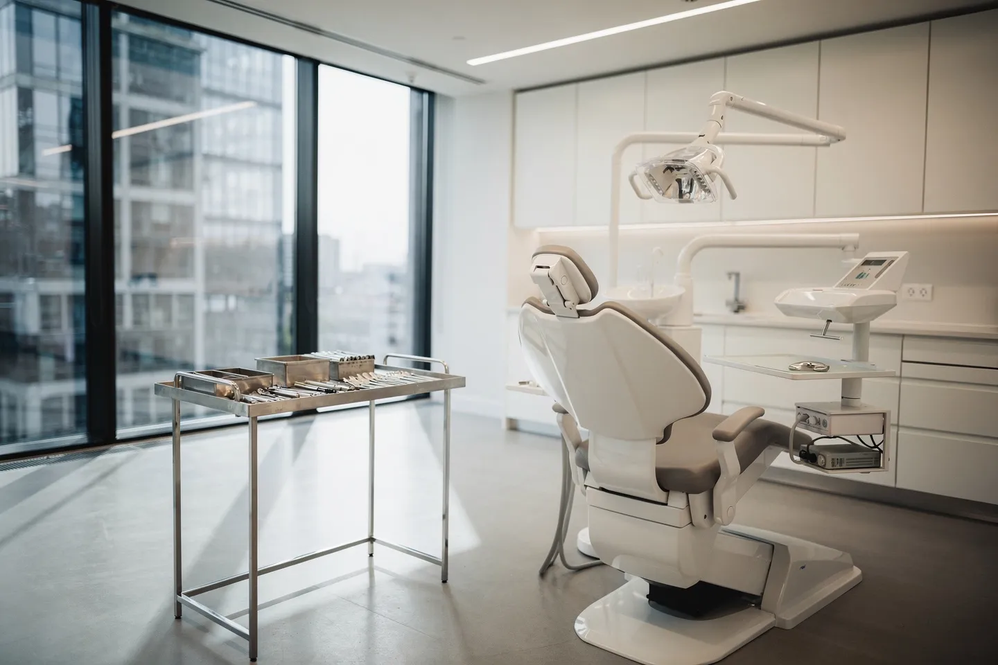 Modernes Zahnarztbüro mit weißem Schrankwerk und minimalistischem Design, Zahnarztstuhl im Vordergrund