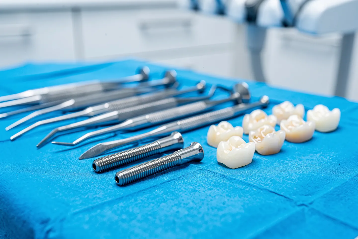 Präzise Zahninstrumente und Implantate liegen auf einem sterilen blauen Tuch in einer Zahnarztpraxis