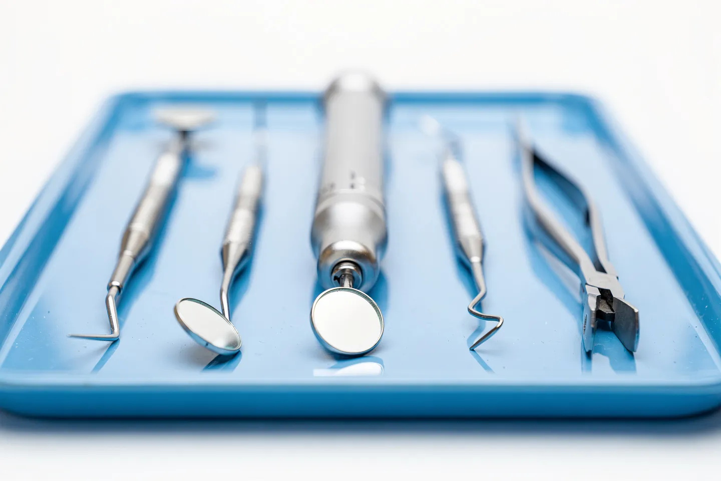 Präzise Zahnarztinstrumente ordentlich auf einem blauen sterilen Tablett angeordnet