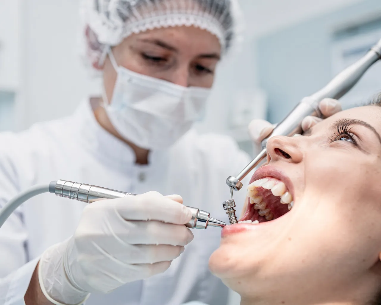 Ein Zahnarzt in weißem Kittel und Maske arbeitet präzise an Zahnimplantaten in einer modernen Klinik