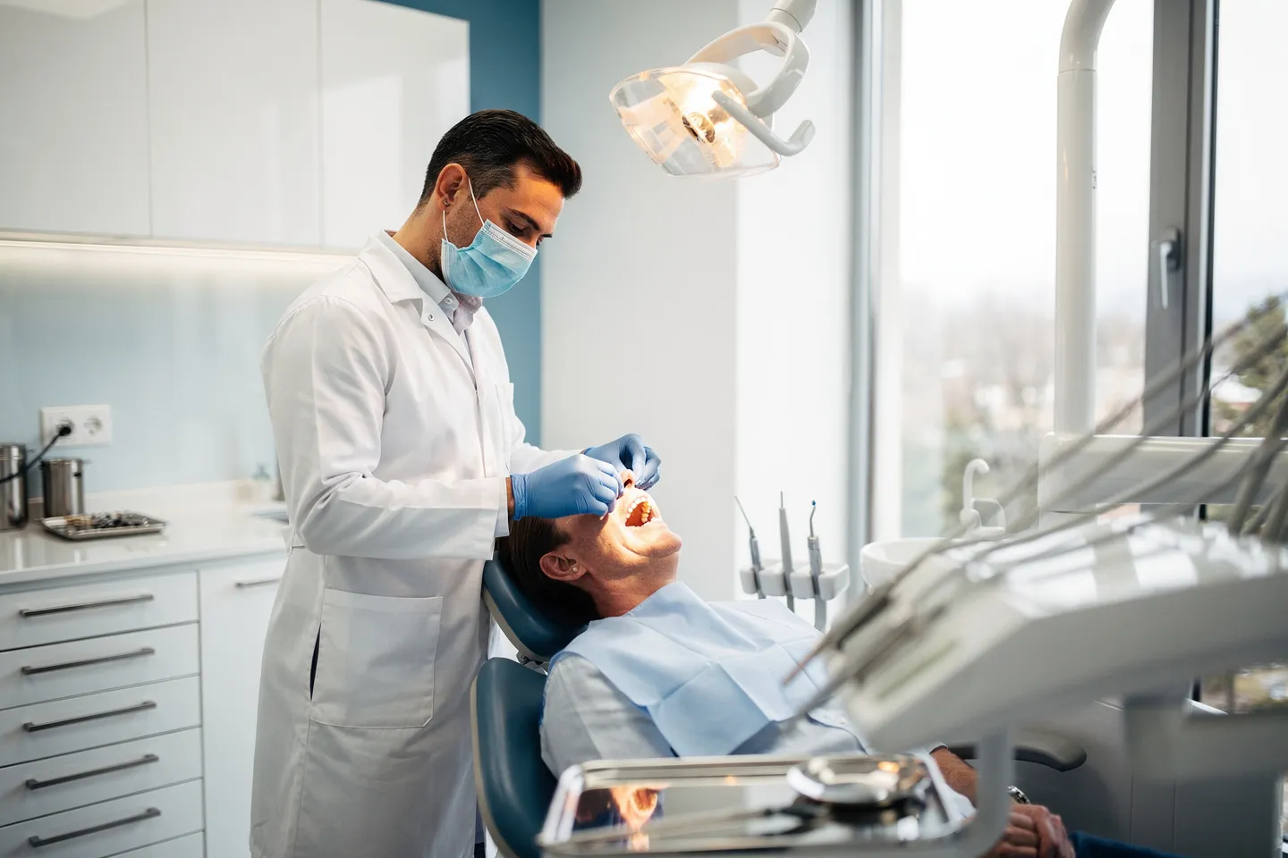 Ein Zahnarzt untersucht einen Patienten in einer modernen Zahnklinik mit freundlicher Atmosphäre