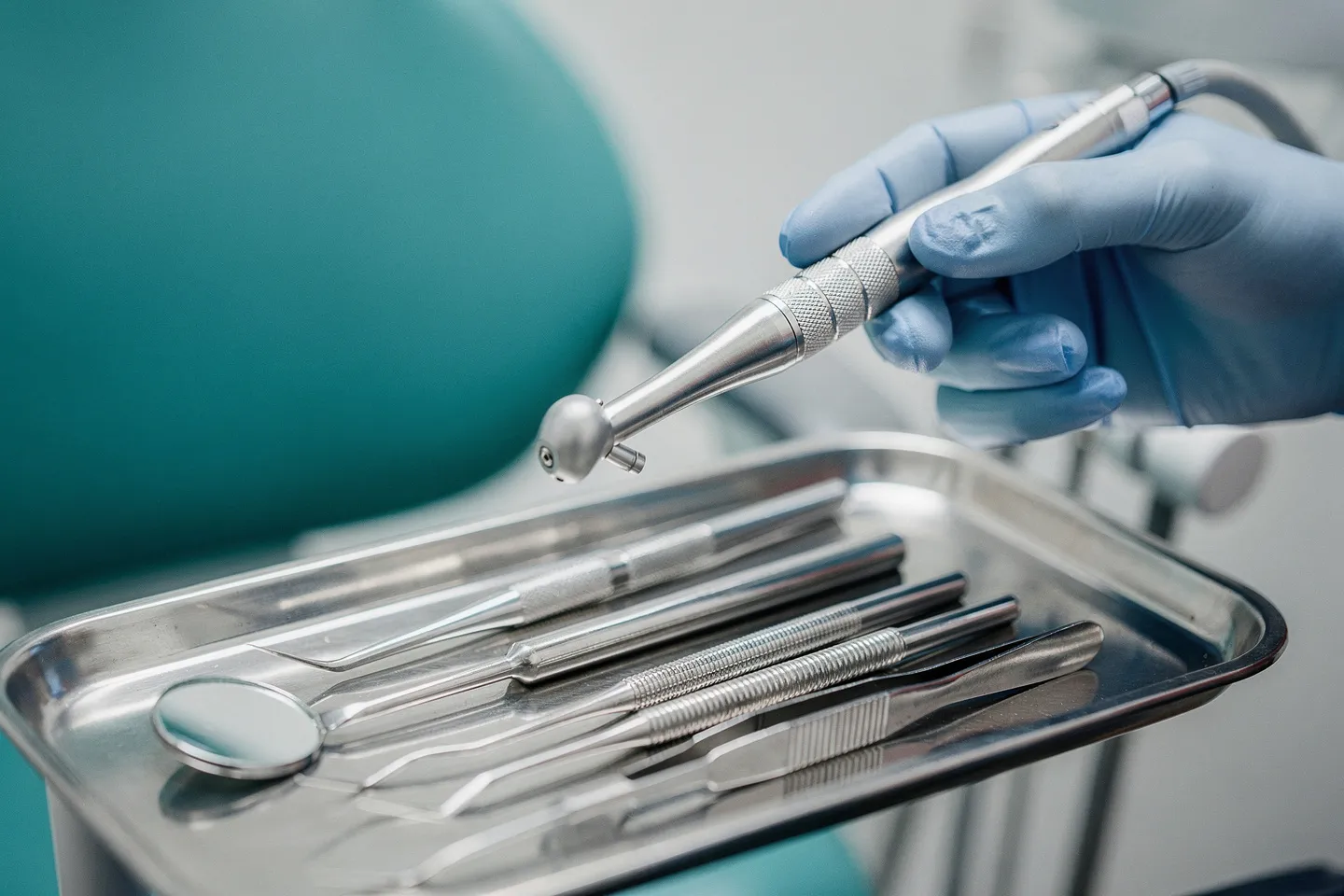 Präzisions-Zahnarztwerkzeuge auf einem sterilen Tablett mit einer Hand, die einen Dentallbohrer hält