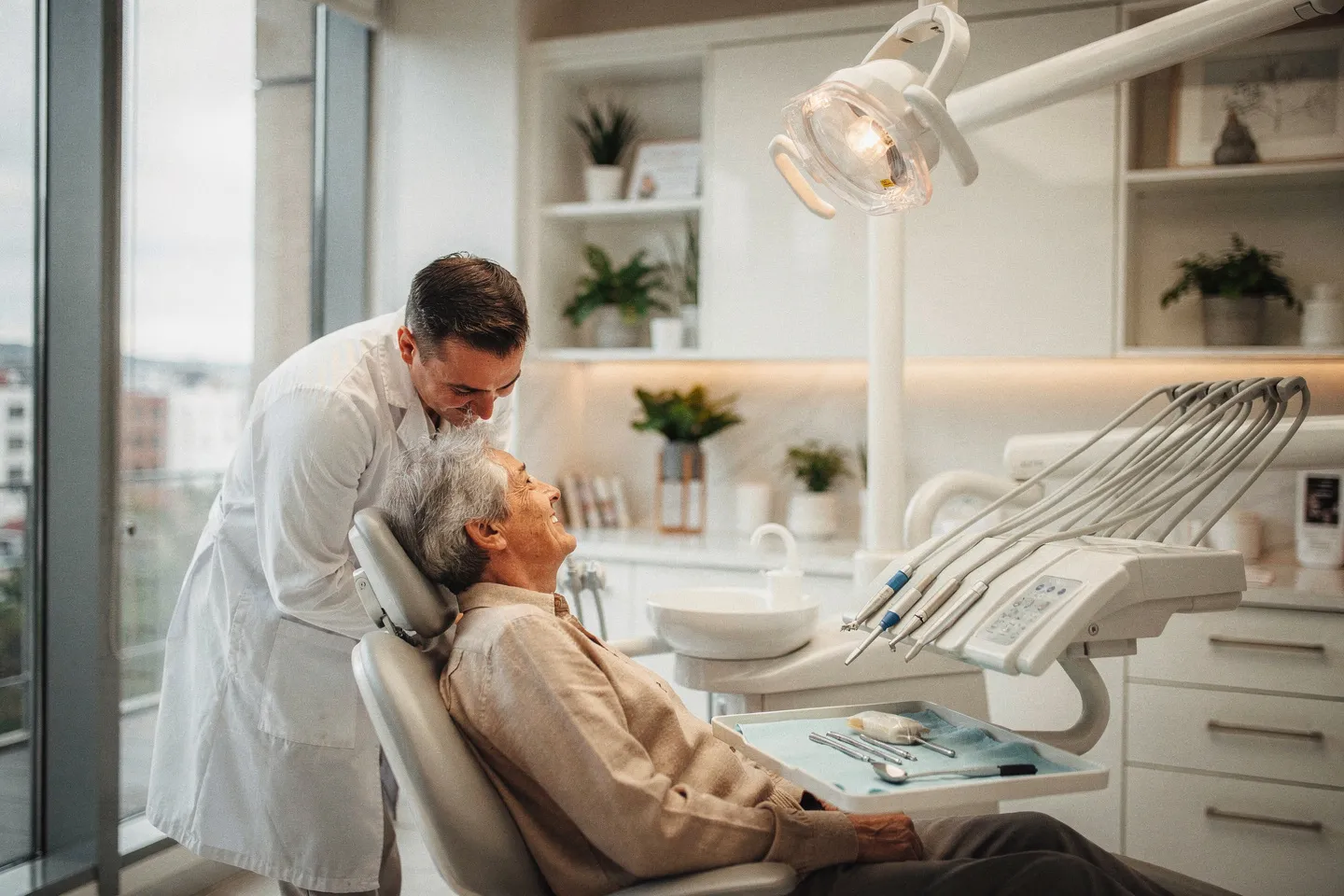 Ein freundlicher Zahnarzt berät einen älteren Patienten im modernen Behandlungszimmer