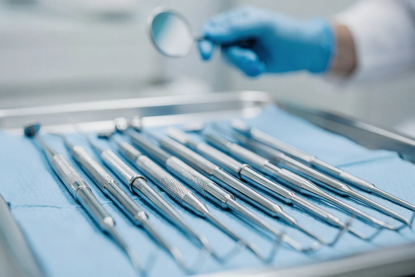 Präzise Zahnarztinstrumente liegen steril auf einem blauen Tablett mit Metallreflexionen
