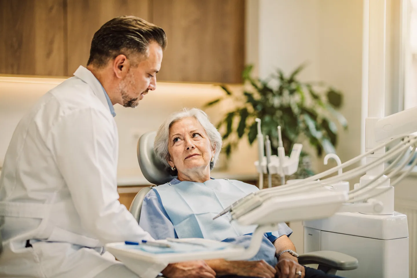 Ein freundlicher Zahnarzt berät einen älteren Patienten in einer modernen Zahnklinik