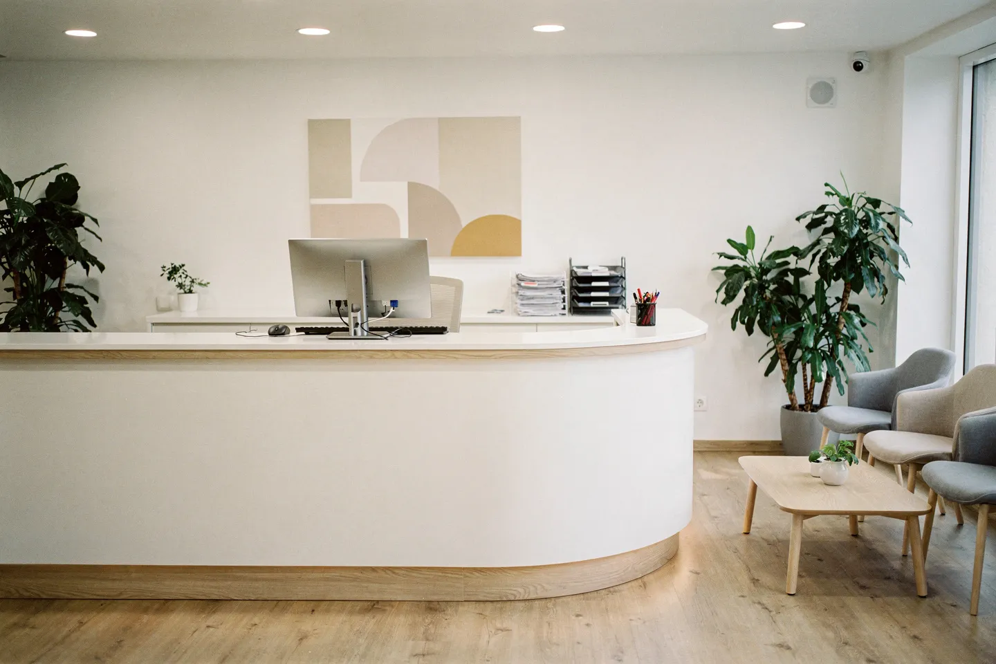 Moderner Zahnarzt-Empfangsbereich mit skandinavischem Design, weißer Theke und minimalistischen Sitzmöbeln