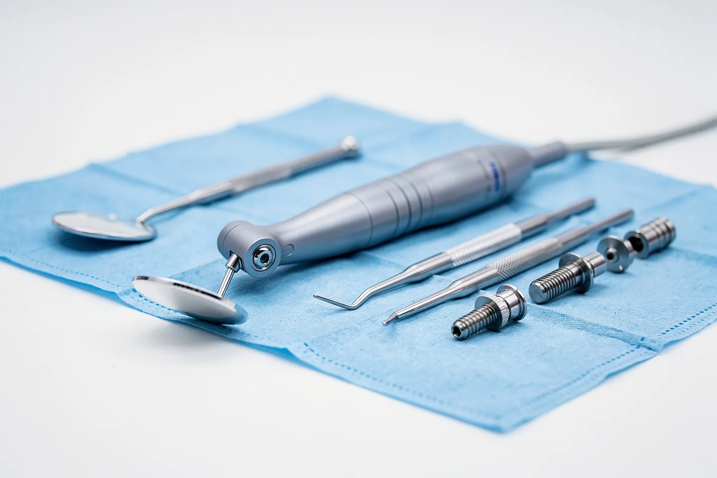 Präzise angeordnete Zahnarztwerkzeuge auf blauem sterilen Tuch mit Implantatkomponenten