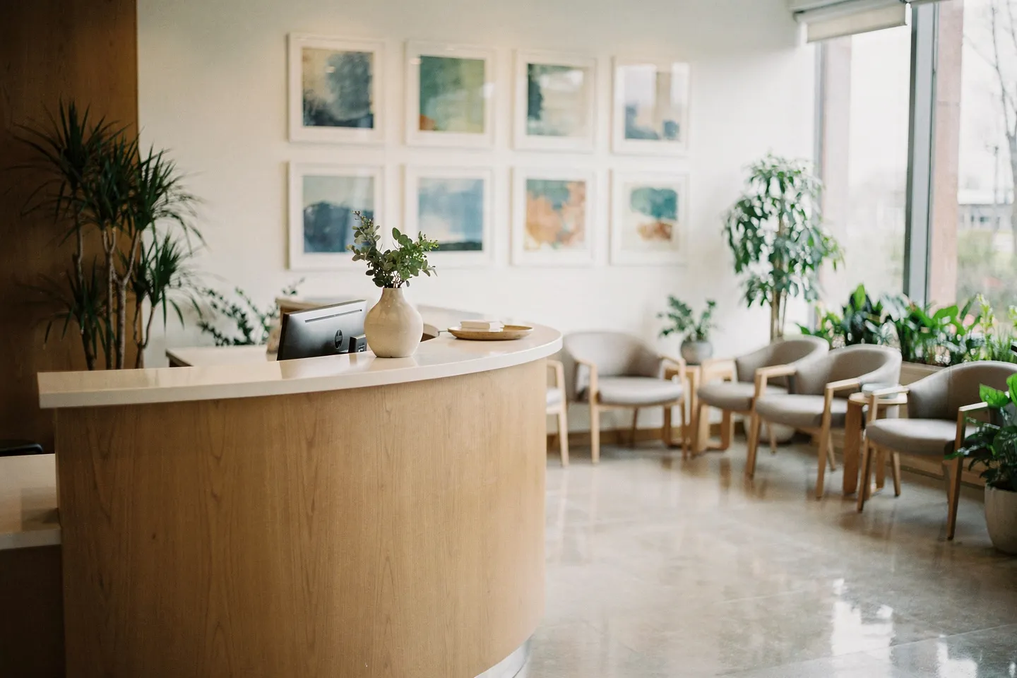 Modernes Zahnarzt-Wartezimmer mit geschwungenem Empfangstisch, bequemen Sesseln und abstrakter Kunst
