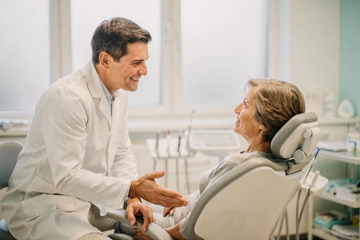 Ein freundlicher Zahnarzt hört einem Patienten in einem modernen Behandlungsstuhl zu