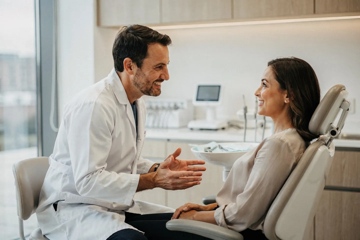 Ein Zahnarzt in weißem Kittel berät lächelnd einen Patienten in einer modernen Praxis