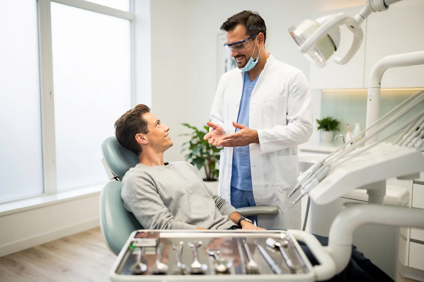 Eine freundliche Zahnärztin erklärt Behandlungsoptionen zu einem Patienten im modernen Behandlungsstuhl