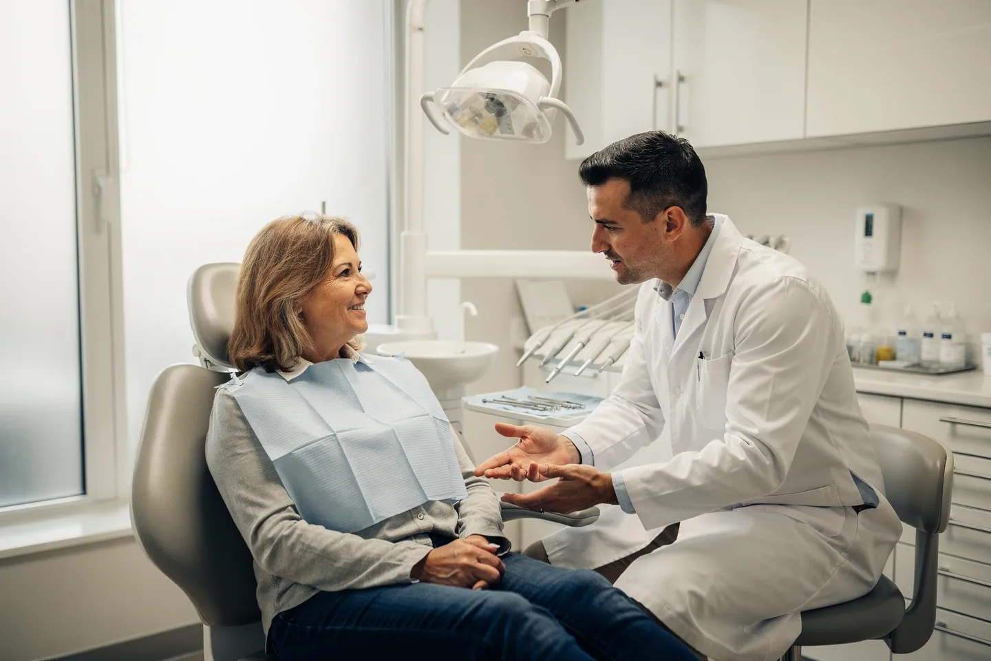 Ein Zahnarzt erklärt einer Patientin Behandlungsoptionen in einem modernen Behandlungszimmer