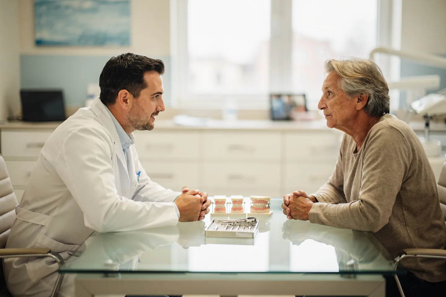 Ein Zahnarzt bespricht Behandlungsoptionen mit einem Patienten an einem modernen Glastisch