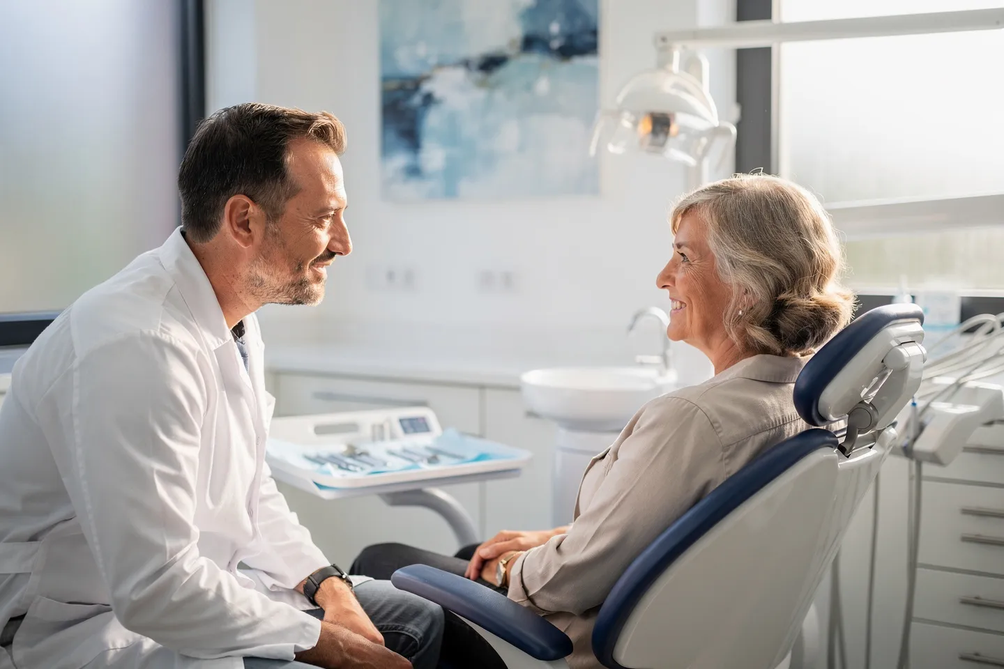 Ein freundlicher Zahnarzt berät einen lächelnden Patienten in einem modernen Behandlungsstuhl