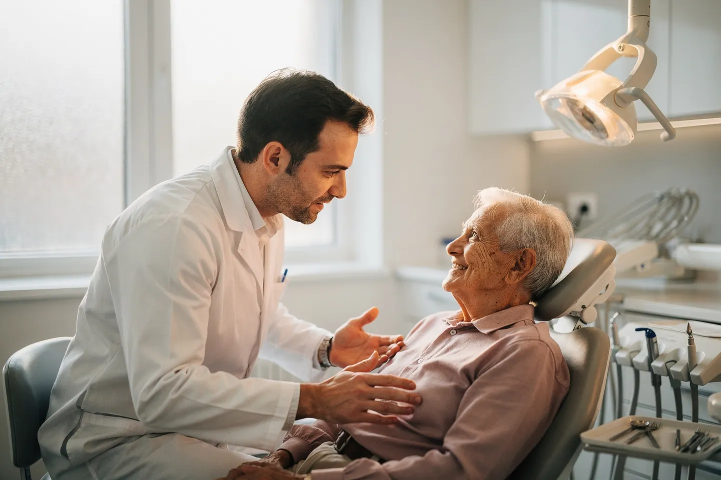 Ein freundlicher Zahnarzt berät einen älteren Patienten in einer modernen Praxis