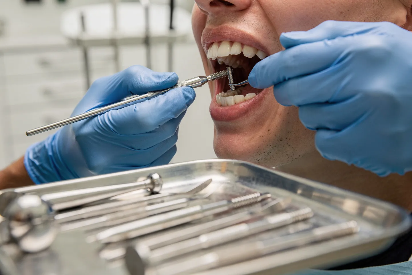 Eine Zahnärztin setzt vorsichtig ein Implantat ein, während Instrumente auf einem Tablett liegen