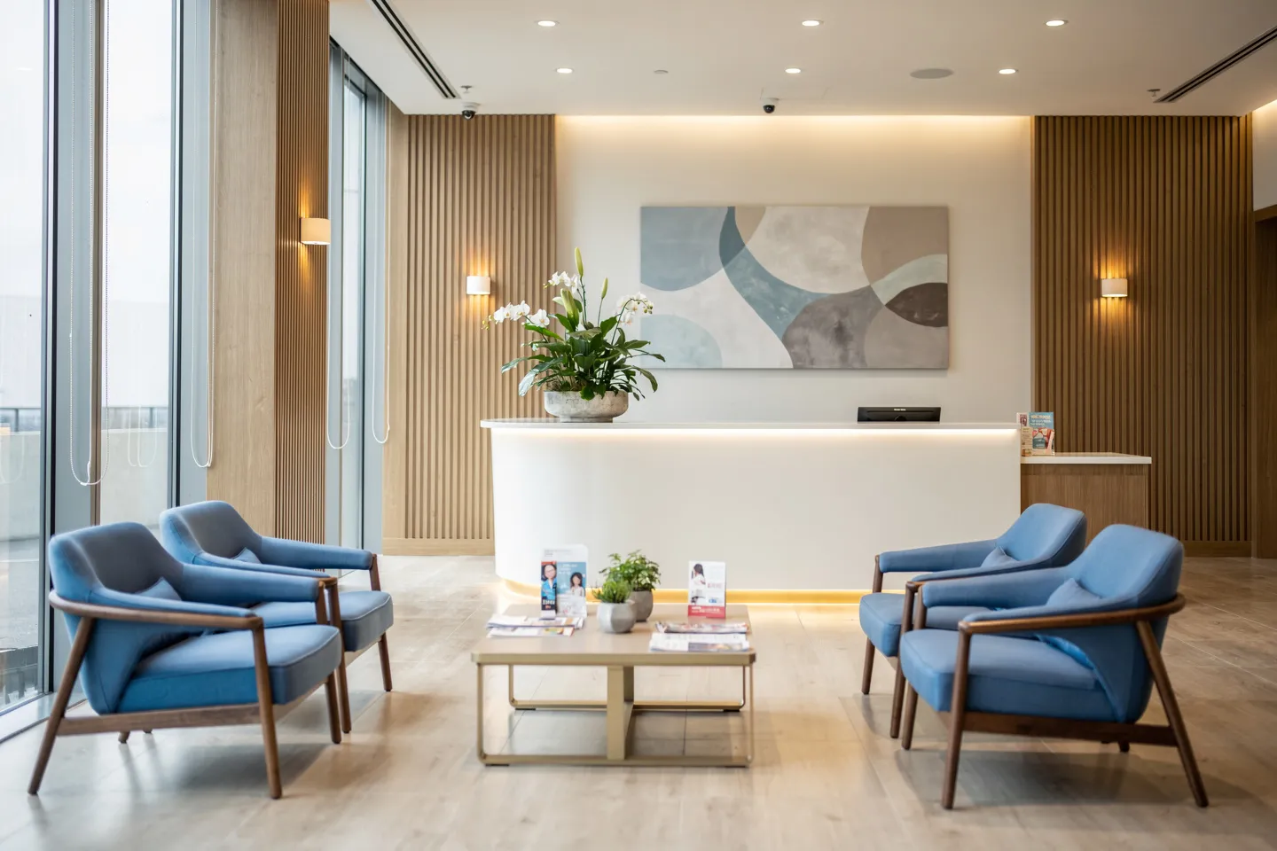 Moderner Zahnarzt-Empfangsbereich mit Holzoptik, blauen Sitzmöbeln und geschwungenem Tresen
