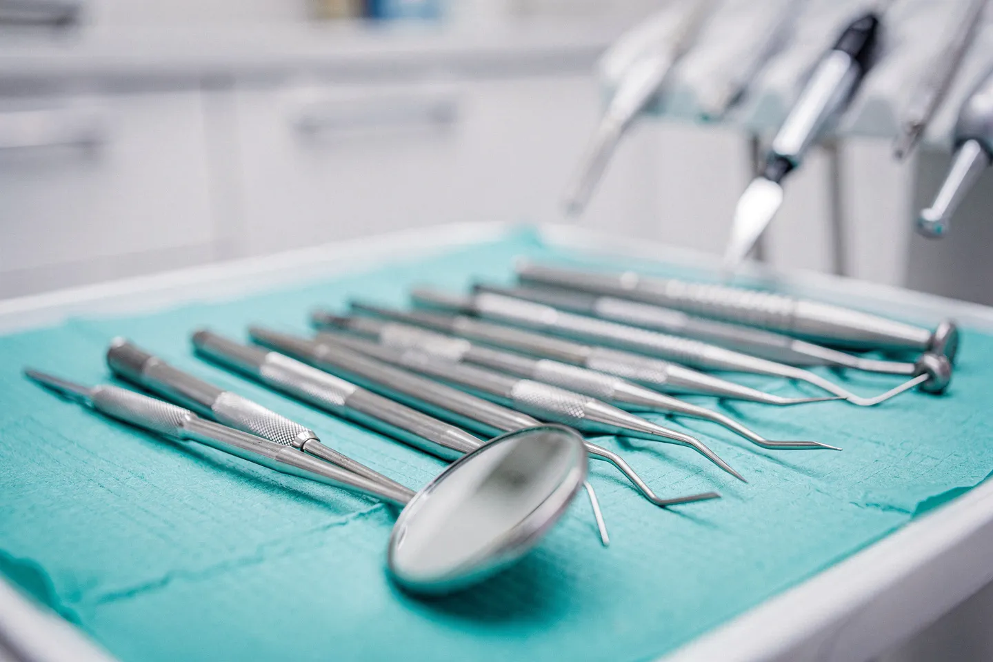 Präzise Zahnarztinstrumente auf einem sterilen türkisen Tablett mit spiegelnden Metallwerkzeugen