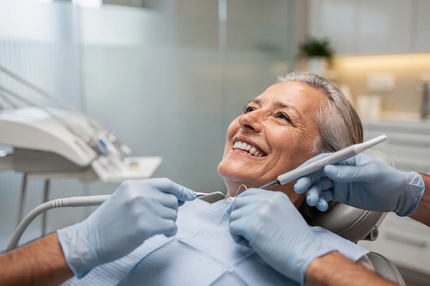 Ein lächelnder Patient mittleren Alters sitzt auf einem modernen Zahnarztstuhl während der Behandlung