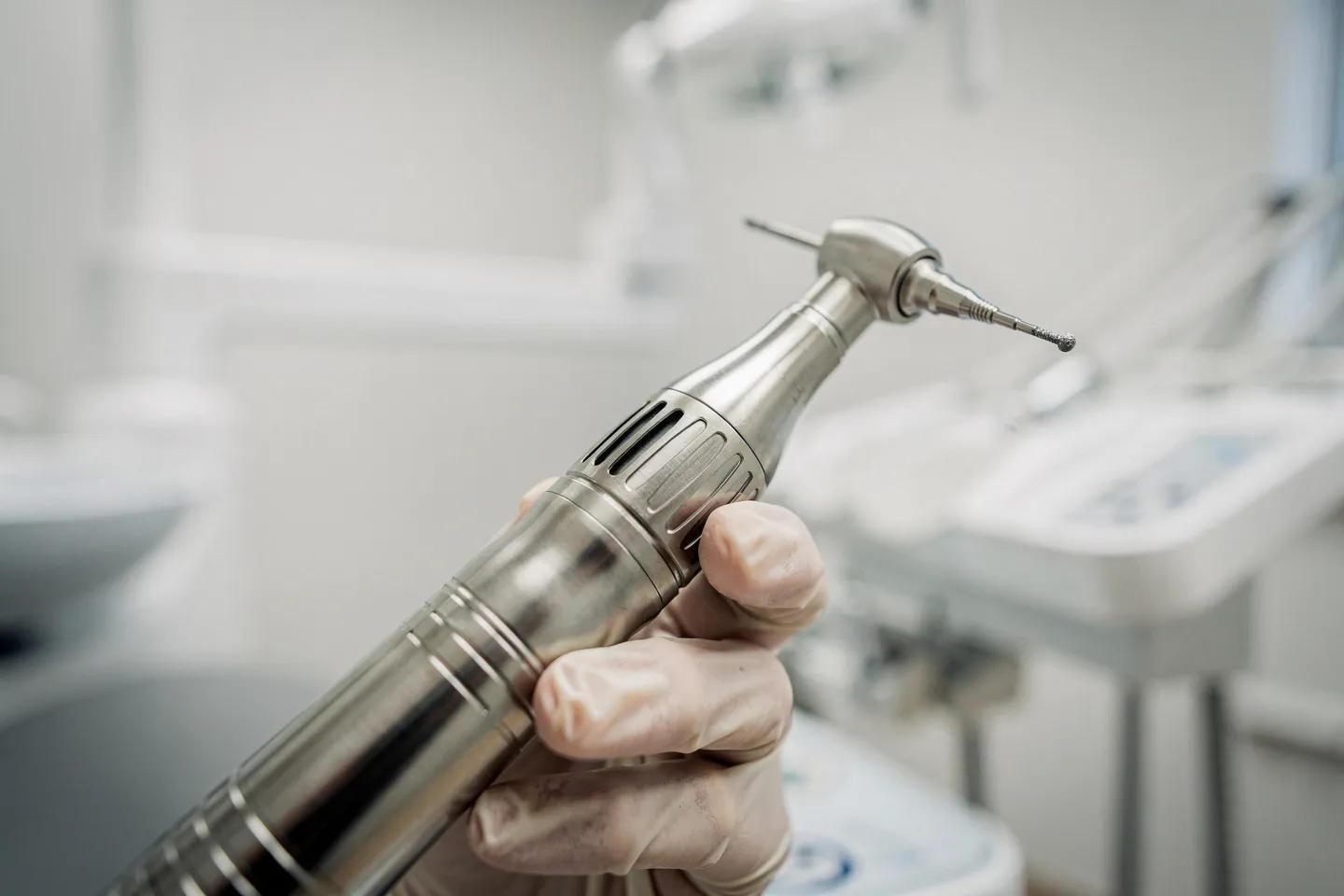 Eine behandschuhte Hand hält einen präzisen Zahnbohrer in einer modernen Zahnarztpraxis