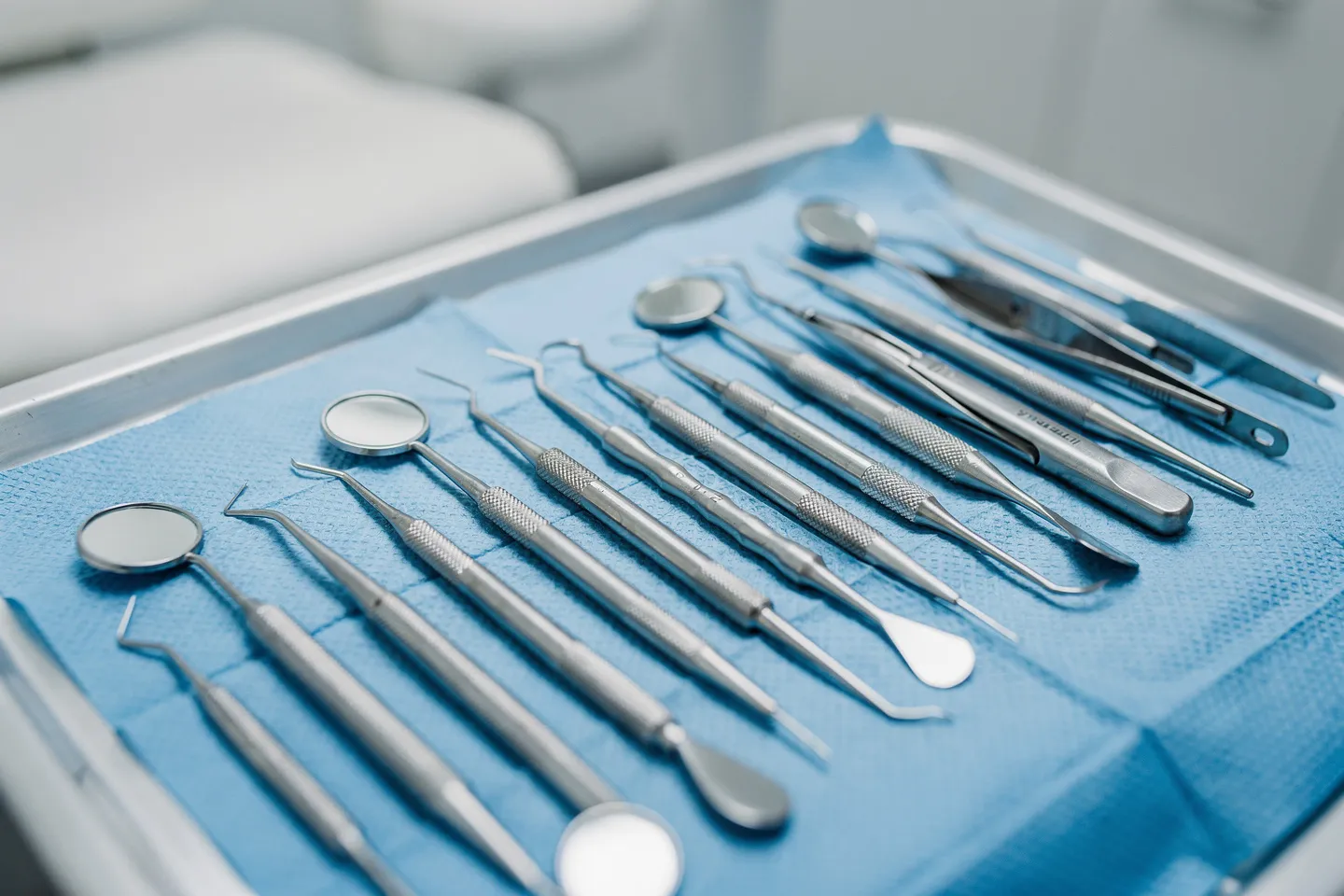 Präzise Zahnarztinstrumente liegen ordentlich auf einem blauen sterilen Tablett