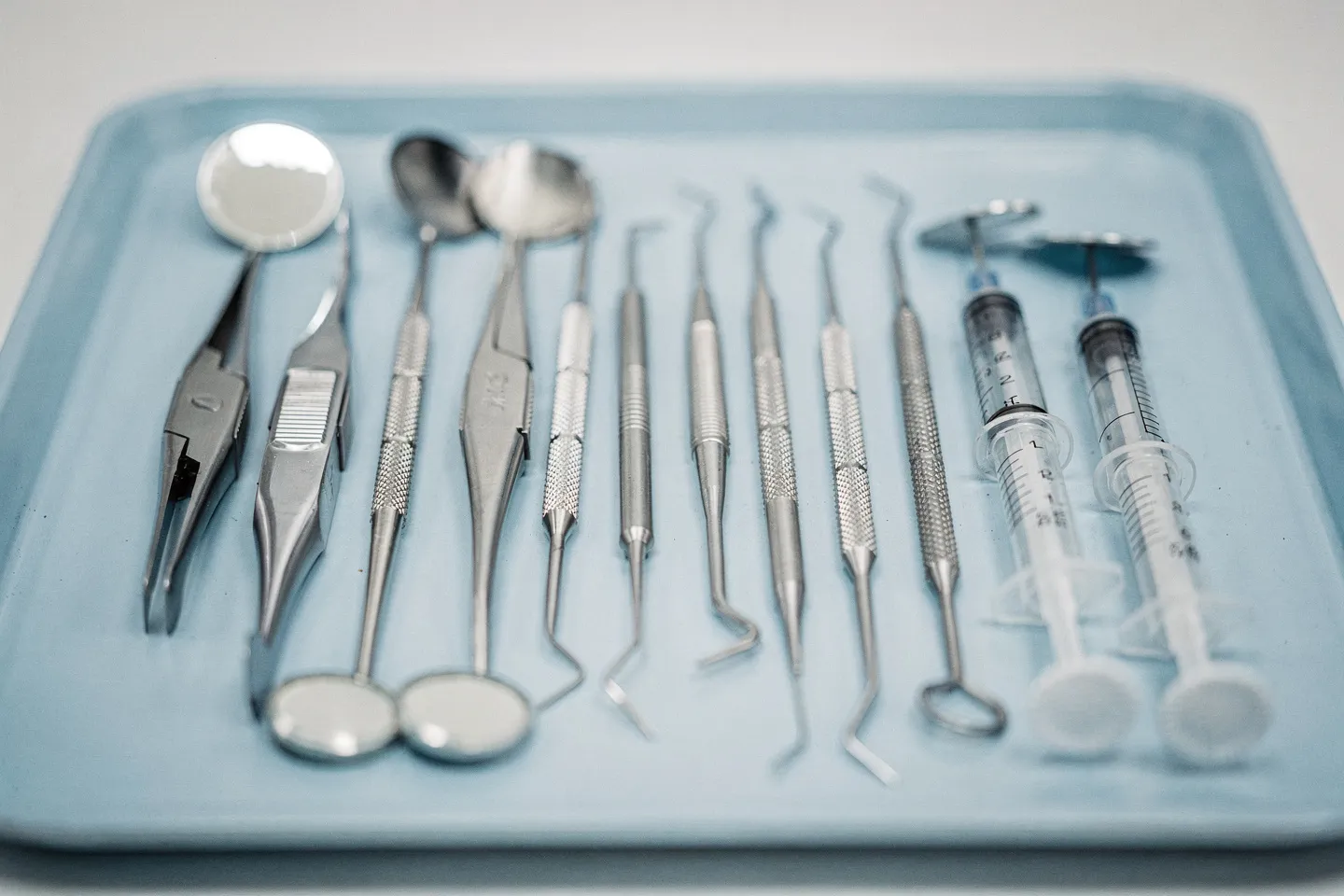 Präzise Zahnarztinstrumente liegen ordentlich auf einem sterilen blauen Tablett