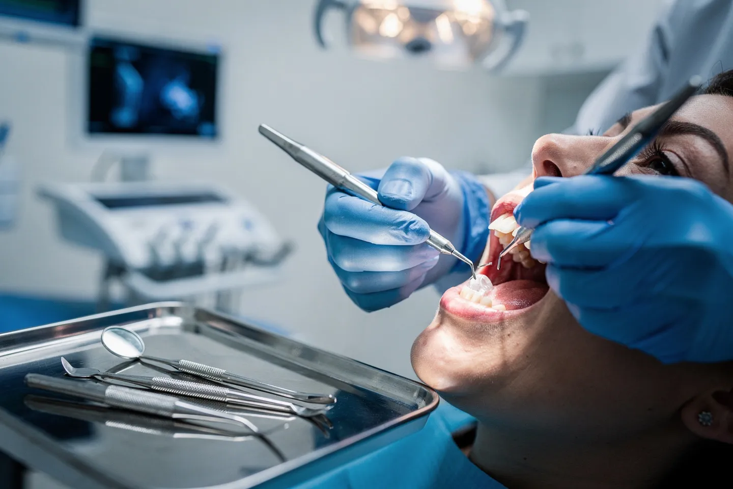 Eine Zahnärztin führt mit Metallinstrumenten eine präzise Behandlung an einem Patienten durch