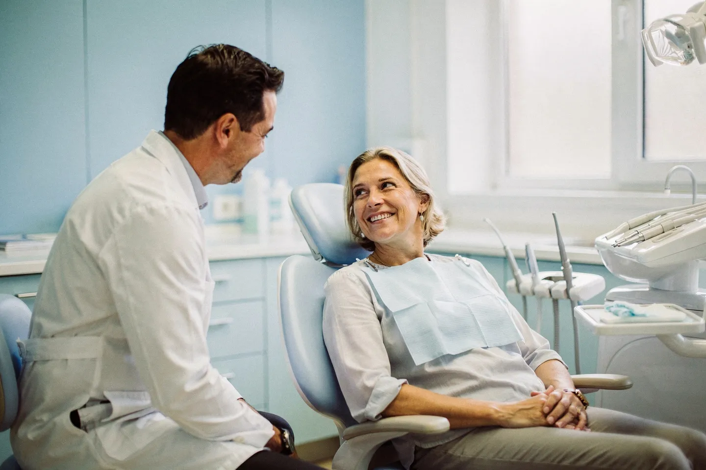 Ein freundlicher Zahnarzt berät einen lächelnden Patienten in einer modernen Zahnarztpraxis
